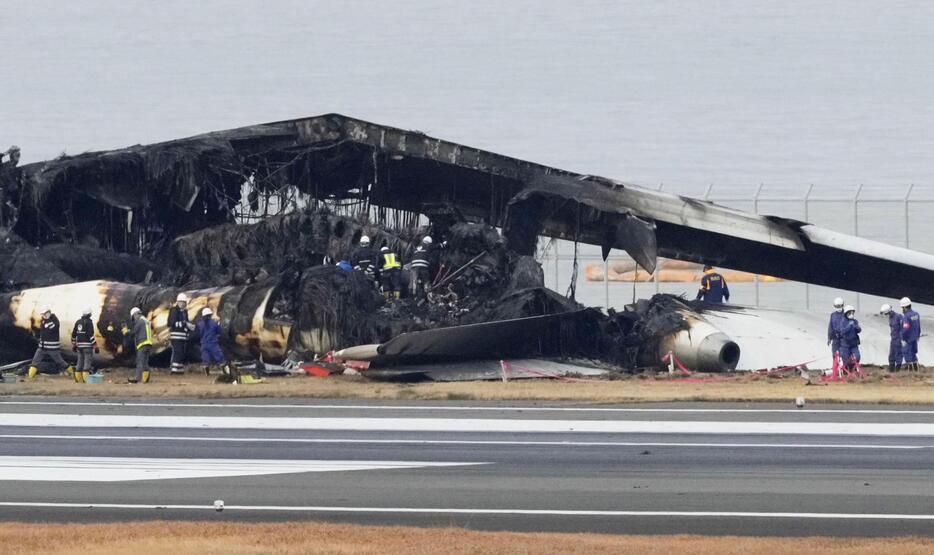 羽田空港の滑走路で炎上し、焼け焦げた日航機を調べる警視庁の捜査員ら＝3日午後3時40分