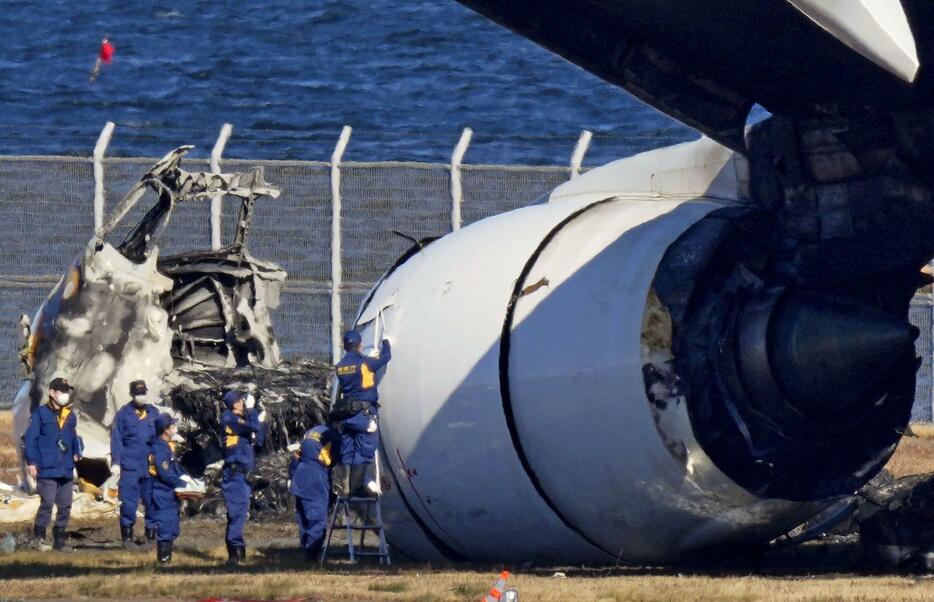 羽田空港の滑走路で炎上し焼け焦げた日航機を調べる警視庁の関係者＝4日午前11時41分