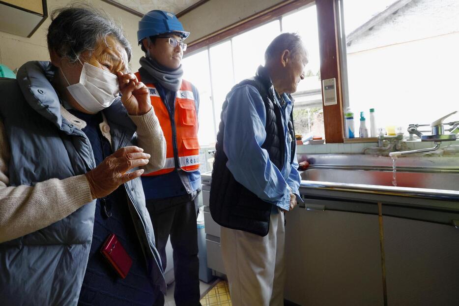 能登半島地震の発生から3週間ぶりに自宅の蛇口から水が流れ、涙を流して喜ぶ下孝子さん（左）。右は夫の和雄さん＝22日午後、石川県輪島市三井町洲衛