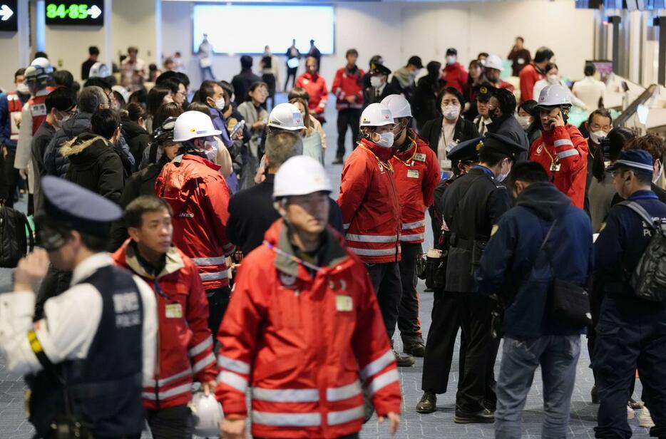 羽田空港で避難した乗客の対応に追われる職員ら＝2日午後8時21分