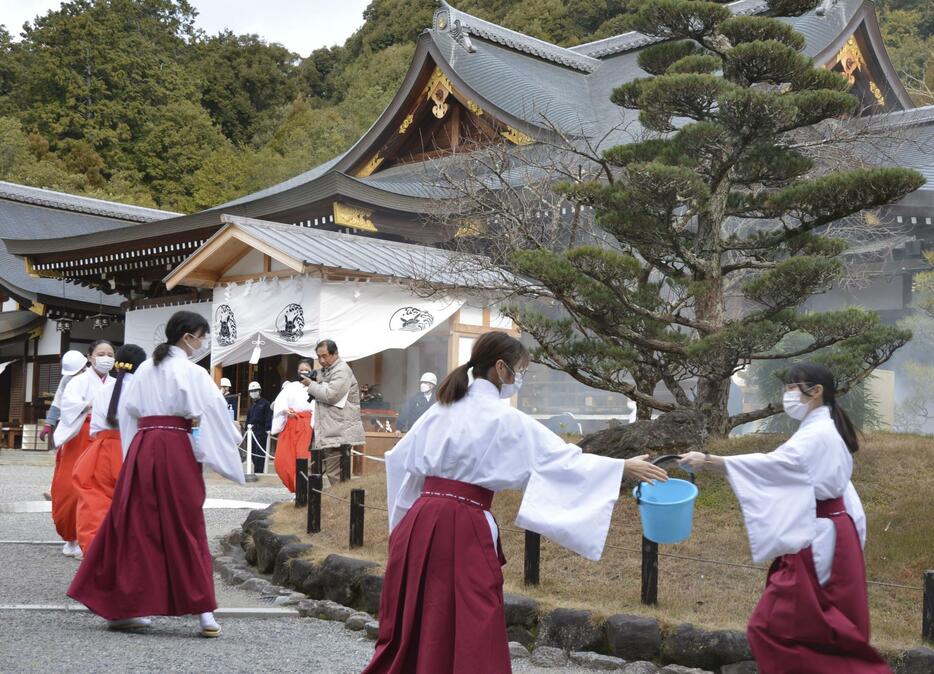 大神神社で実施された防火訓練で、バケツリレーをする巫女や職員ら＝23日午後、奈良県桜井市