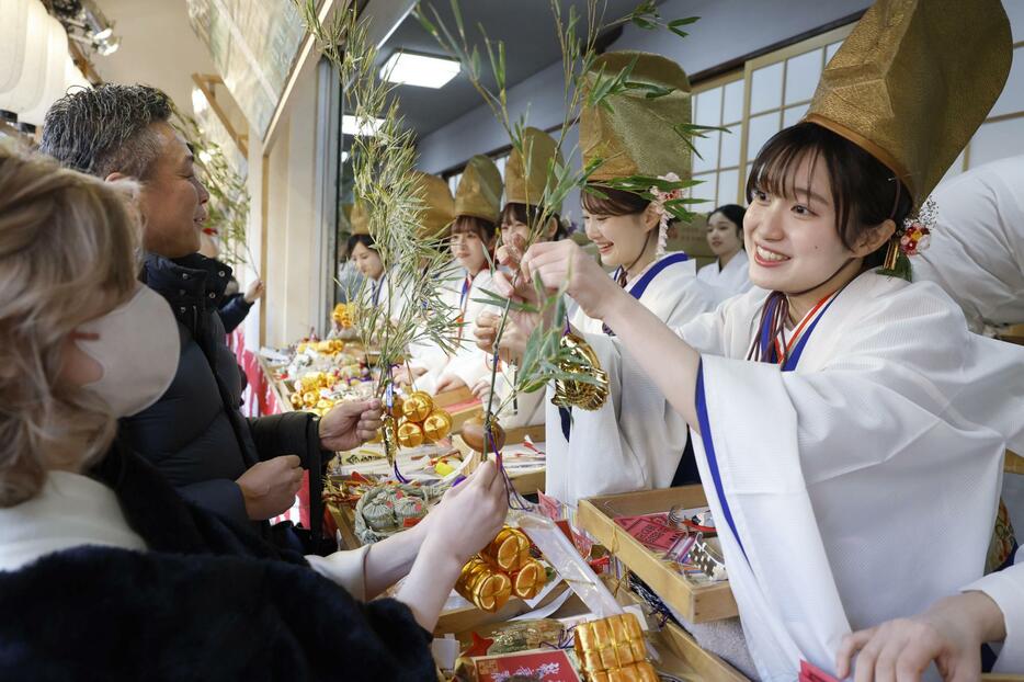 大阪市の今宮戎神社で「十日えびす」の幕開けとなる「宵えびす」が始まり、参拝客のササに縁起物を結びつける福娘＝9日午後