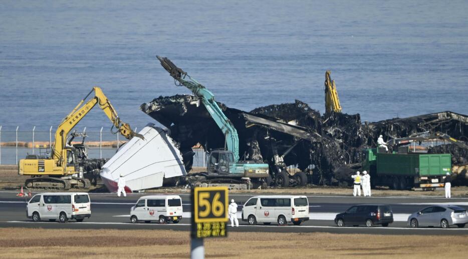 羽田空港の滑走路で進む日航機の撤去作業。翼部分が切断された＝5日午前