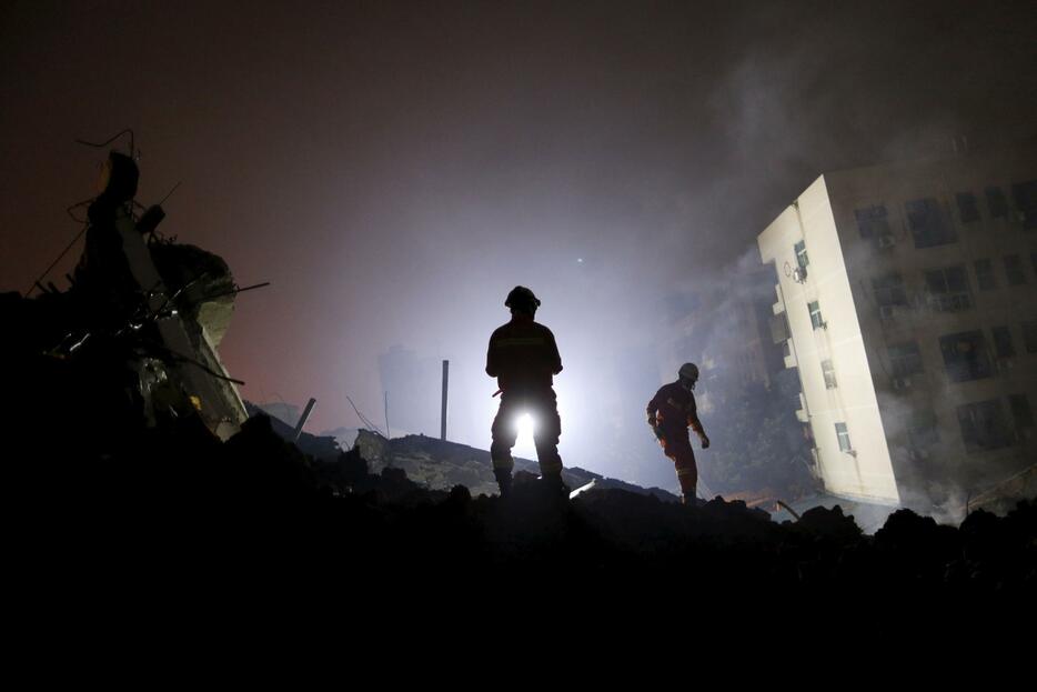 暗闇の中に倒れた建物と土砂が浮かび上がる＝2015年12月20日（写真：ロイター/アフロ）