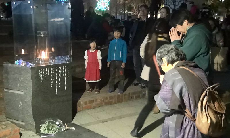 [写真]1.17希望の灯りに手を合わせる人たち＝6日午後7時半ごろ、神戸市で