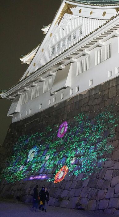［写真］大阪城の石垣には、来場者らが別の場所で撮った笑顔の花が映し出されていた＝13日午後7時40分ごろ、大阪市中央区で