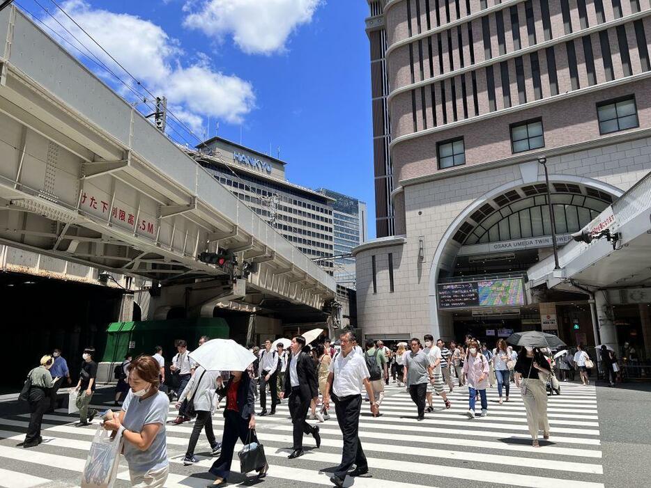 ［写真］強い日差しを浴びながら歩く人々＝20日、大阪市北区で