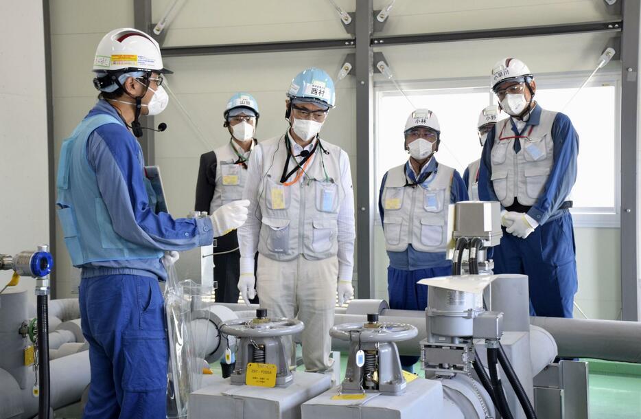 東京電力福島第1原発で、緊急時に処理水の供給を止める遮断装置を視察する西村経産相（左から3人目）＝10日（代表撮影）