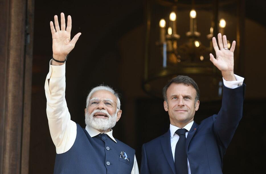 14日、パリで手を振るフランスのマクロン大統領（右）とインドのモディ首相（AP＝共同）