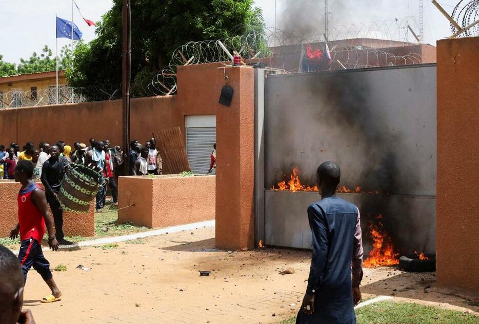 ニジェールの首都ニアメーのフランス大使館に火を放つ軍事政権支持派のデモ隊＝30日（ロイター＝共同）