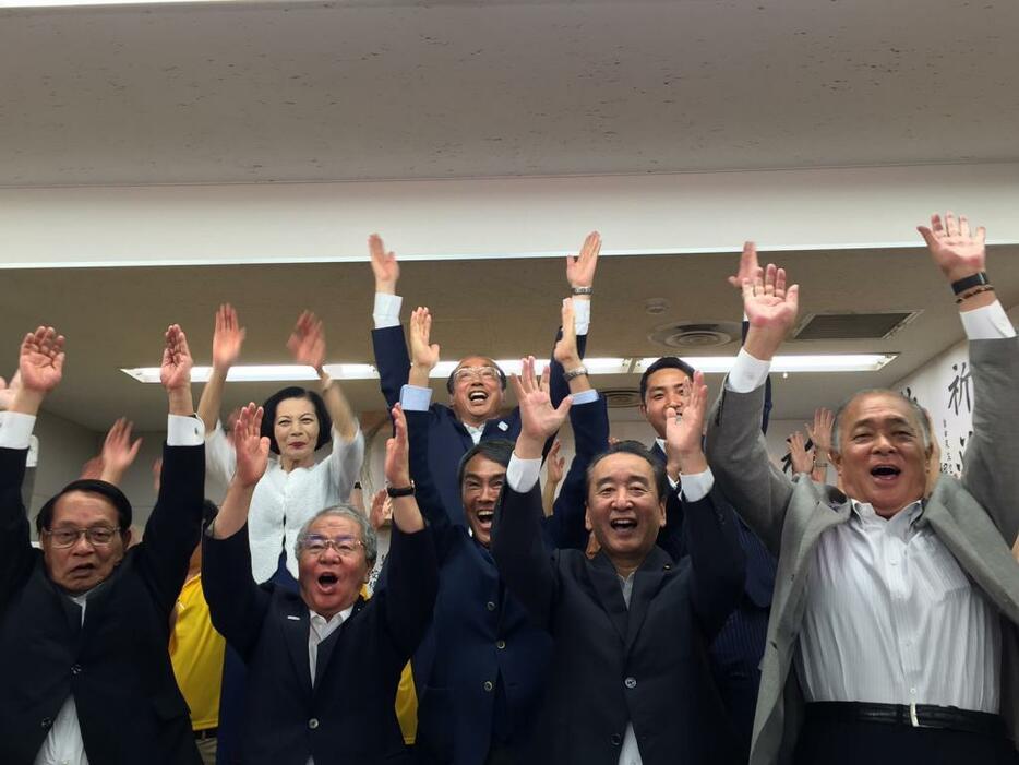 [写真]万歳する中川雅治氏ら（中央奥）