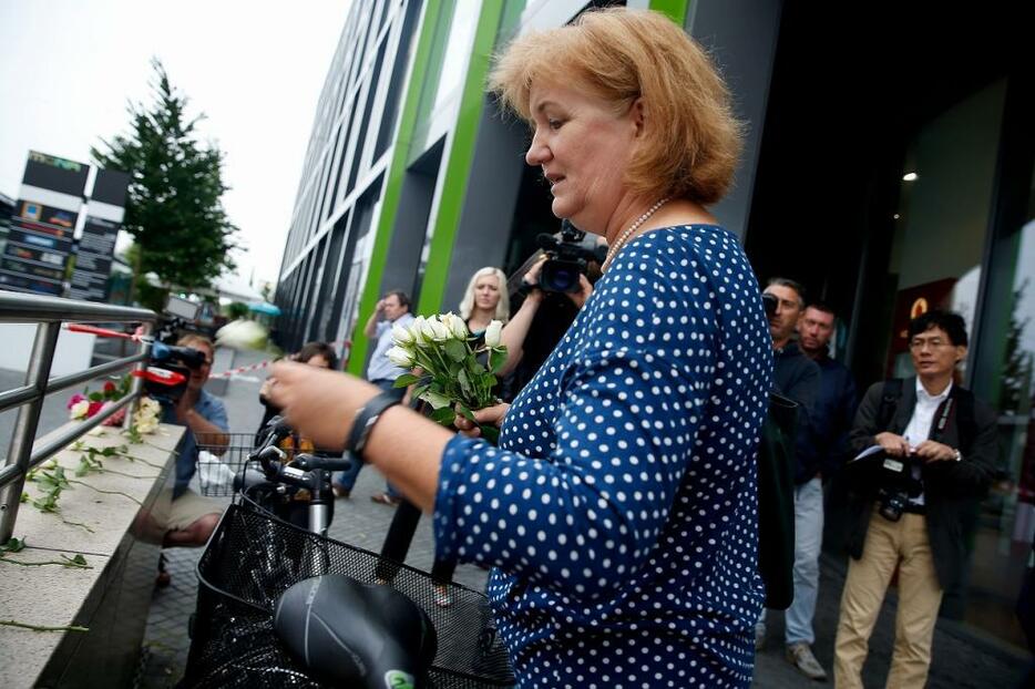 [写真]銃乱射が起きたミュンヘンのショッピングセンター近くで花を手向ける女性（ロイター/アフロ）