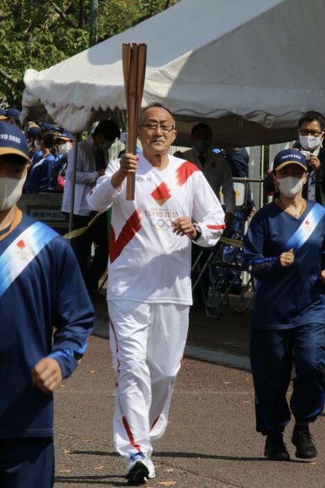 ［写真］前日に続き、聖火ランナーが元気に走った。写真は第一走者の西村成生さん。1964年東京五輪で聖火ランナーの伴奏者を務めた＝14日午前10時すぎ、大阪府吹田市で