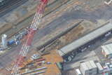赤白クレーンのところをアップで捉えると工事用の杭が打たれているすぐそばに石垣が露出しているのが見える。「6街区」の築堤は調査せずに再埋没させるとのこと（2021年3月30日、吉永陽一撮影）。