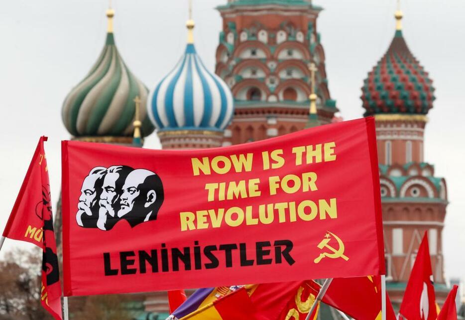 [写真]ロシア革命の十月革命から100年を前に、モスクワの赤の広場でレーニンらを描いた旗を掲げる共産党支持者ら（ロイター/アフロ）