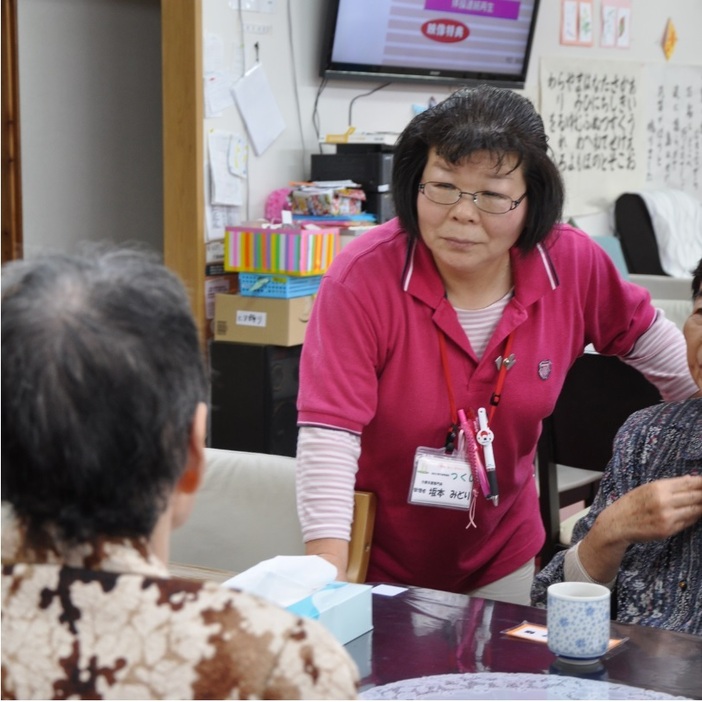 来所した高齢者に体調を尋ねる坂本みどりさん。熊本県高森町のデイサービスセンターで（撮影：木野千尋）