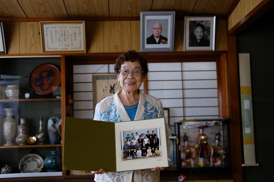 孫やひ孫に囲まれた家族写真を手にする武村さん＝22日午前、那覇市（撮影：山本宏樹/deltaphoto）