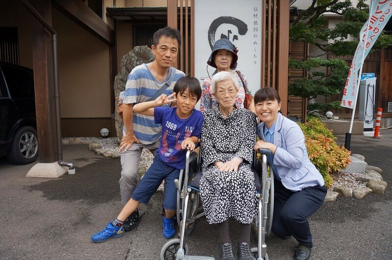 [写真]中井康子さんのふるさと福井への里帰り旅行を実現した中井家一行。前列中央が中井康子さんで、左が孫の悠仁くん、右がTCAの大島美佐子さん。後列左が康子さんの次男浩之さん