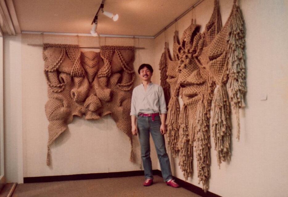 ファイバーアートの展示作品前に立つ大塚さん（1982年）