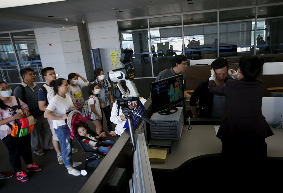 乗客の体温を測る空港職員＝2015年6月2日（写真：ロイター/アフロ）