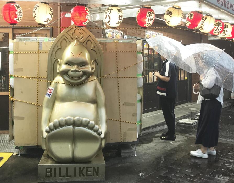 ［写真］しっかりとロープで固定されたビリケンさんの大看板。雨風がきても倒れないようロープでしっかり固定されている＝15日午後6時半ごろ、大阪市浪速区で