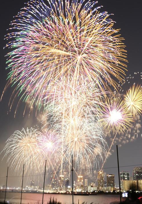 ［写真］色鮮やかな大輪がなにわの空に。後方は大阪梅田のビル街＝10日午後8時すぎ、大阪市内で