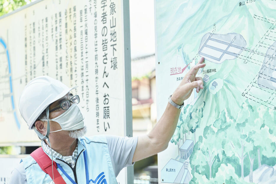 壕の入り口にある地図で案内を始める松樹さん。ガイド希望者は同祈念館まで