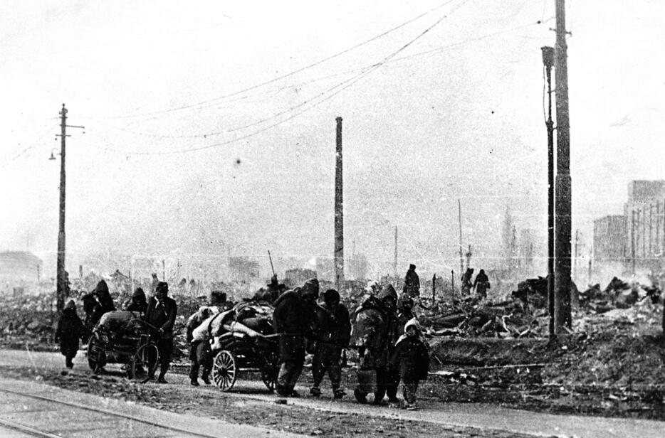 1945年3月10日の未明、東京下町の住宅密集地を狙い、米軍の爆撃機B29が大量の焼夷弾を落とす。大空襲直後の朝、白煙の漂う焼け跡を歩く人たち（1945年3月10日　読売新聞／アフロ）