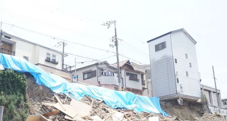 [写真]写真左側は建物が倒壊した跡でブルーシートに覆われていた