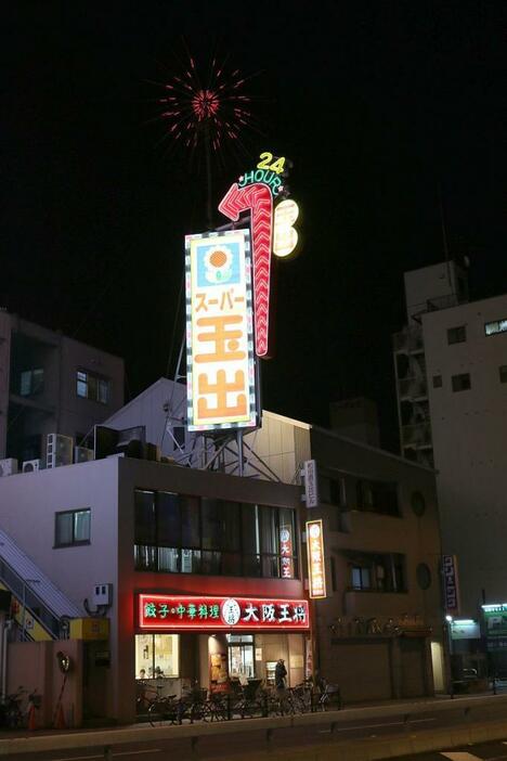 [写真]1号店、2号店は商店街の中にあるため、大通りの飲食店上に「スーパー玉出」の案内看板を出している＝13日夜、大阪市西成区で