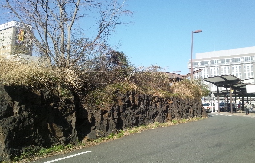 黒茶い岩があるJR三島駅北口。1万年前に富士山から流れた溶岩だという=三島市