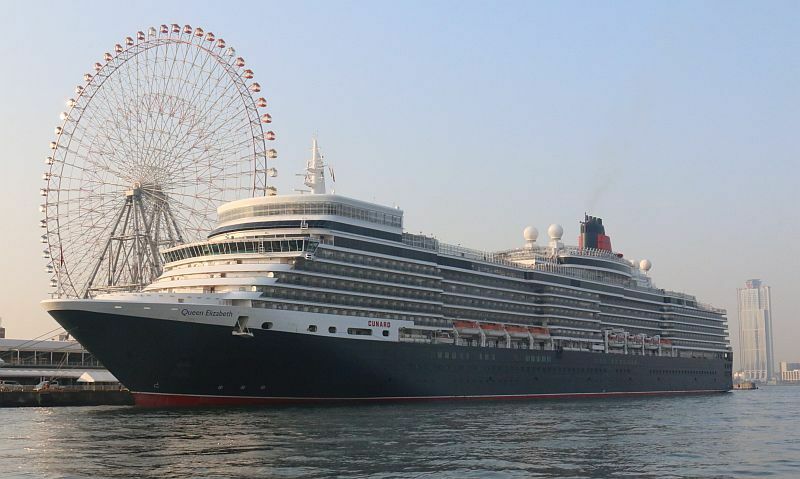 [写真]朝日を浴びる大阪港に入港した豪華クルーズ客船「クイーン・エリザベス」。左後方には天保山大観覧車、右には住之江区の大阪府庁咲洲庁舎も見える＝15日午前7時すぎ、大阪市港区で（撮影：柳曽文隆）