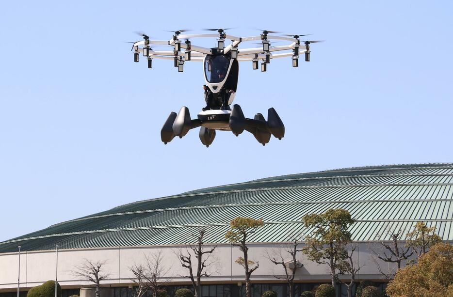 ［写真］大阪城を背に旋回する空飛ぶクルマ。下は大阪城ホール＝14日午後1時40分ごろ、大阪市中央区で