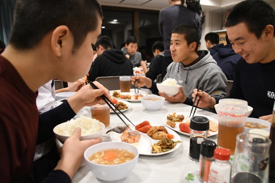 「球心寮」で夕食を食べながら談笑する野球部員たち＝多摩市で