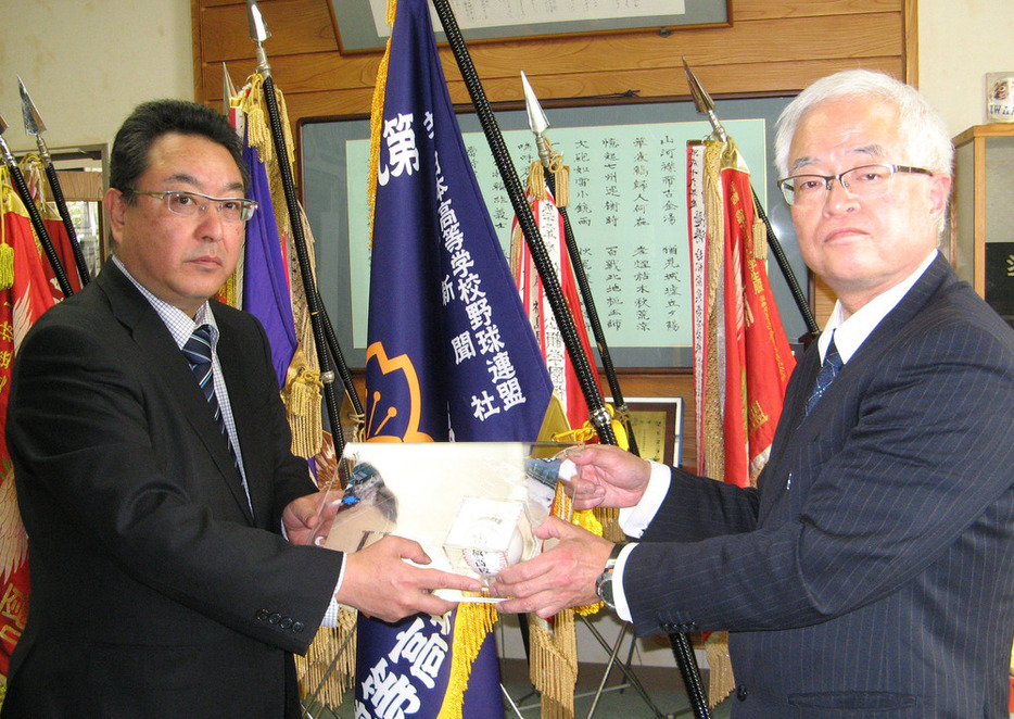 木部浩行・県毎日会浜通り方部会長から記念ボールを受け取る磐城高の阿部武彦校長（右）＝福島県いわき市平の同校で