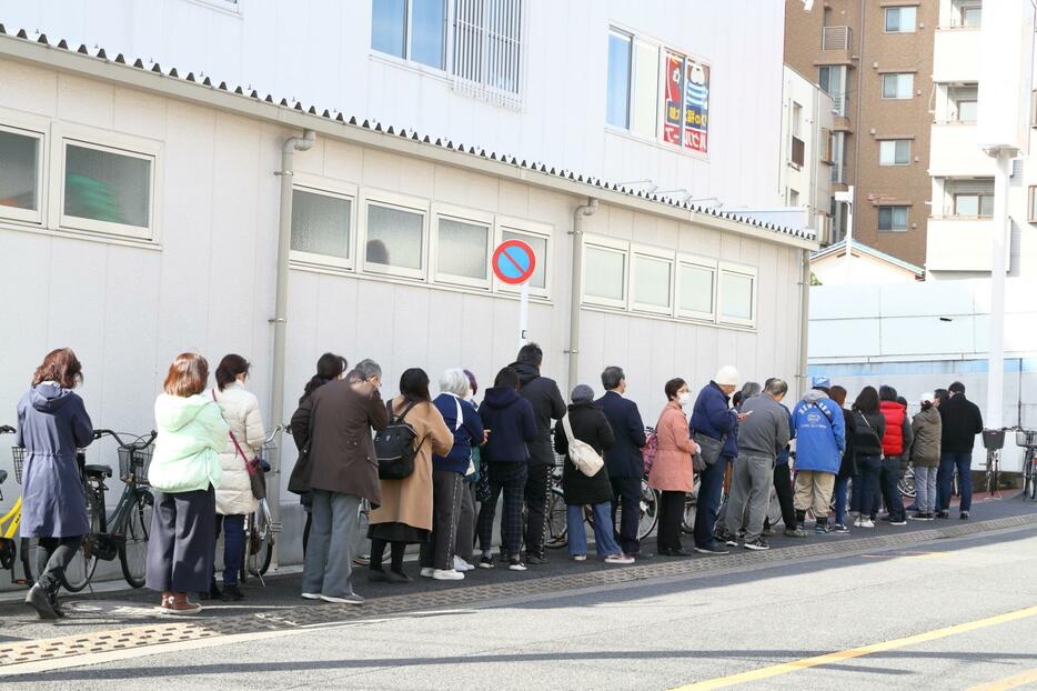 トイレットペーパーやマスクの購入のため、ドラッグストア脇に並ぶ買い物客ら。東京都、3月3日撮影。（写真：西村尚己/アフロ）