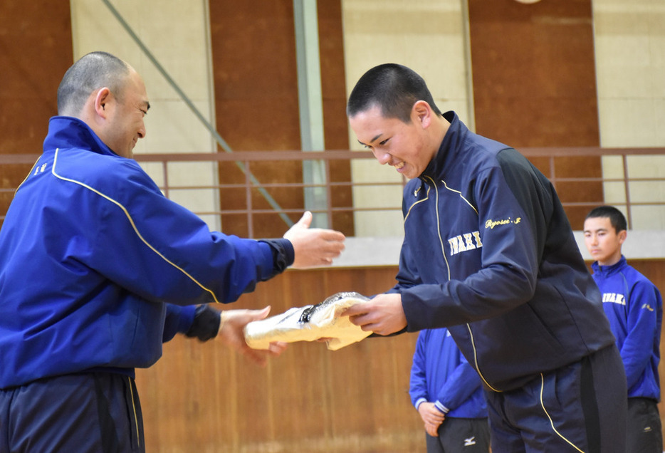 岩間涼星主将にユニホームを渡す木村保監督（左）＝福島県いわき市平の磐城高校で