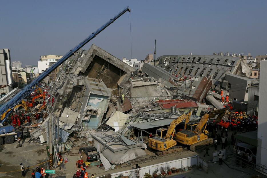 倒壊した建物と投入された捜索用の重機＝2016年2月7日（写真：ロイター/アフロ）