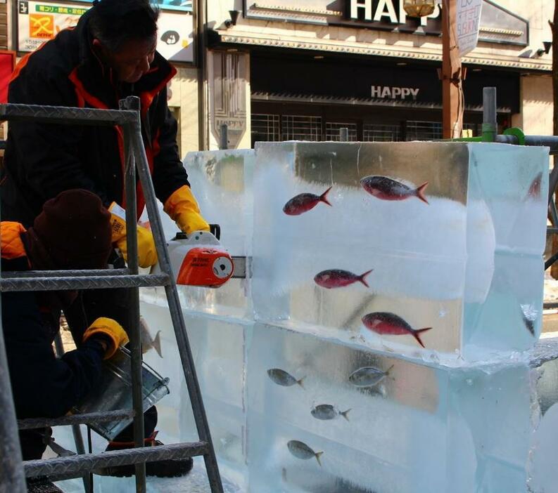 [写真]氷の中を魚が“泳ぐ”中、チェーンソーで氷を削っていく