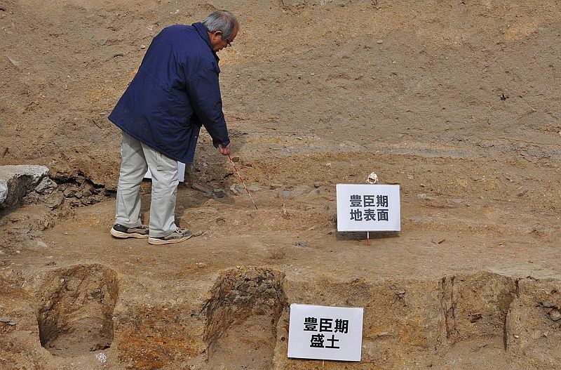 [写真]研究員が立っている場所が豊臣期大坂城の地表面。大坂の陣で焼けた瓦の破片などが点在している＝大阪市中央区大阪城天守閣東南