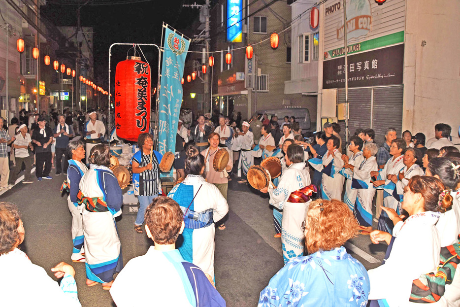 チヂンを打ち鳴らして、輪になって八月踊りを楽しむ参加者＝3日、鹿児島県奄美市名瀬