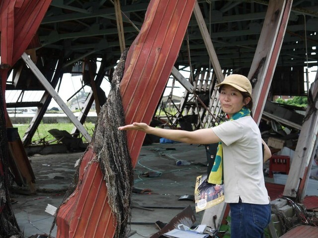 ガイドの宮口さん。キリコ倉庫まで流されてきた海草を指し示している（筆者撮影）