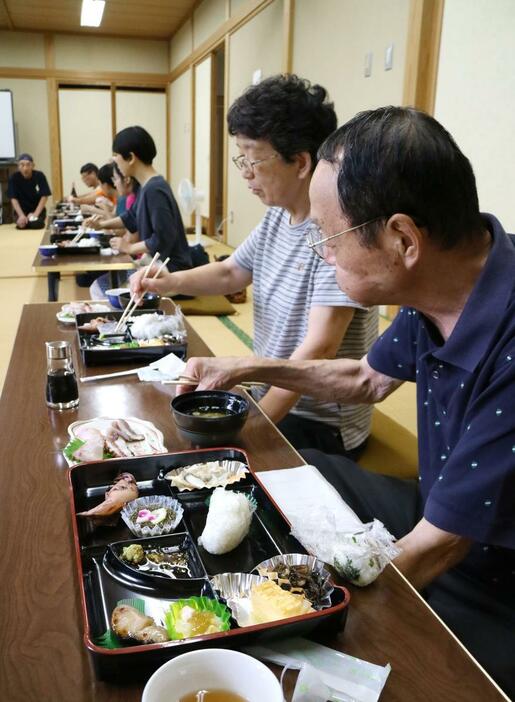 モニター体験で朝食を味わう参加者。刺身などが並んだ御膳を撮影する姿もあった=佐渡市鷲崎