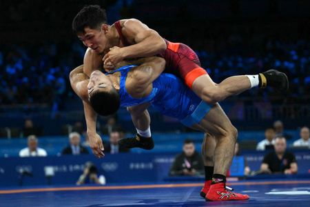 パリ五輪、レスリング男子グレコローマンスタイル60キロ級準決勝。試合に臨むキルギスのジョラマン・シャルシェンベコフ（上）と文田健一郎（2024年8月5日撮影）。