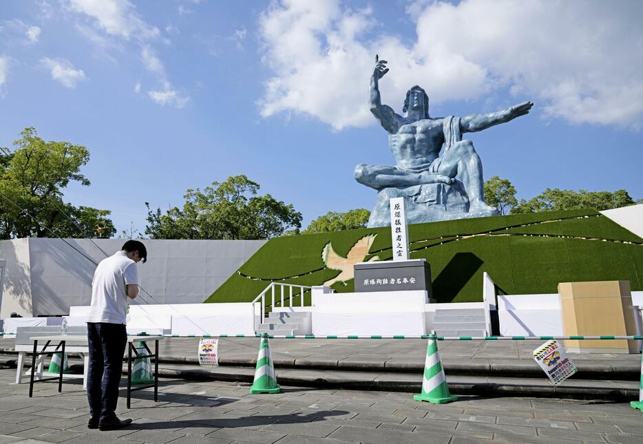 平和祈念像の前で手を合わせる人＝7日午後、長崎市の平和公園