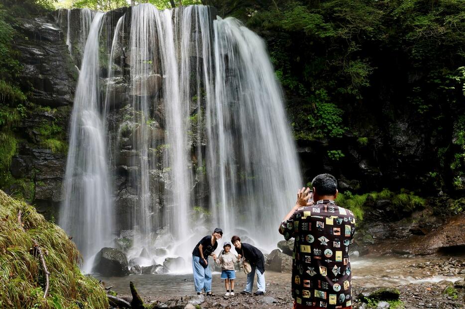 滝を背景に記念写真を撮る家族