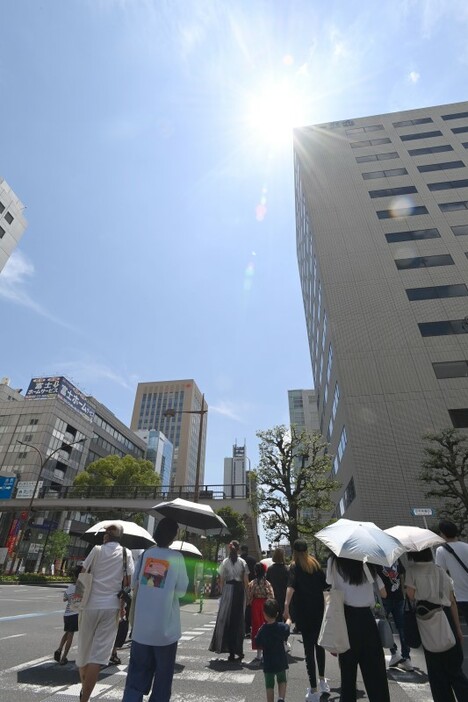 強い日差しの下、日傘を差して歩く人たち＝18日午後0時13分、岡山市北区下石井