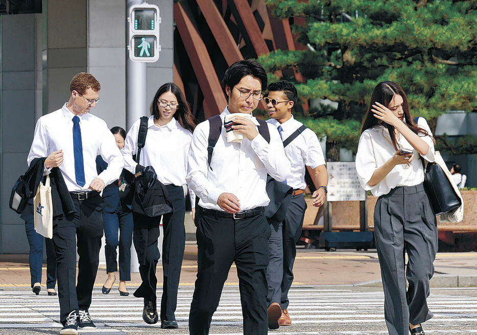 汗を拭いながら出勤する会社員＝１９日午前８時４０分、金沢駅前