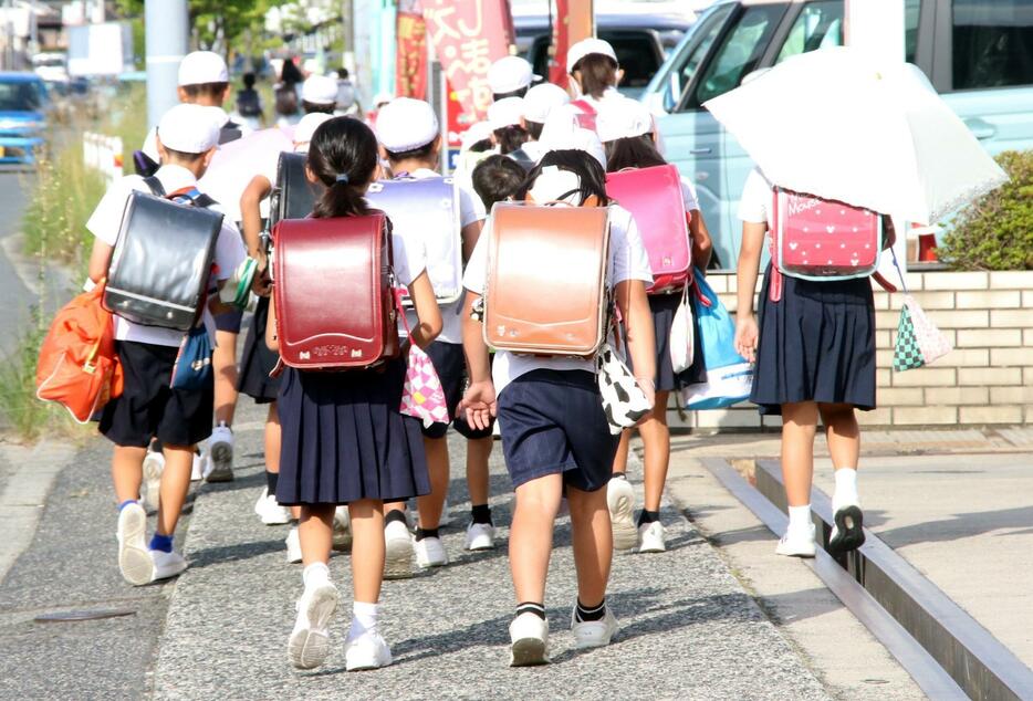 炎天下、集団で登校する福山市内の児童。熱中症対策で日傘を差す姿もあった