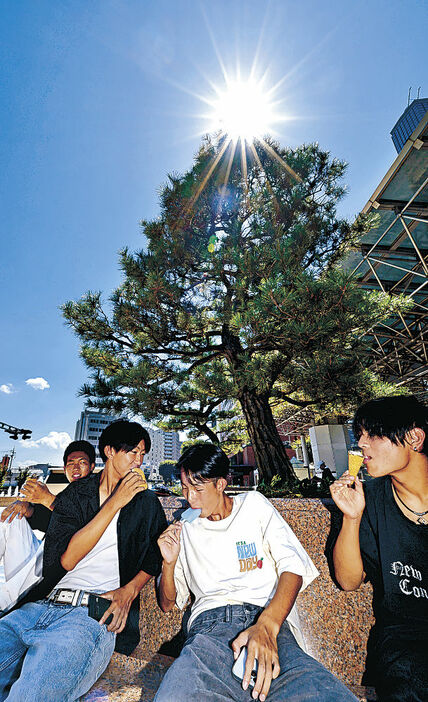 猛烈な暑さの中、アイスを食べて涼をとる人たち＝２３日午前１０時４０分、金沢駅東広場